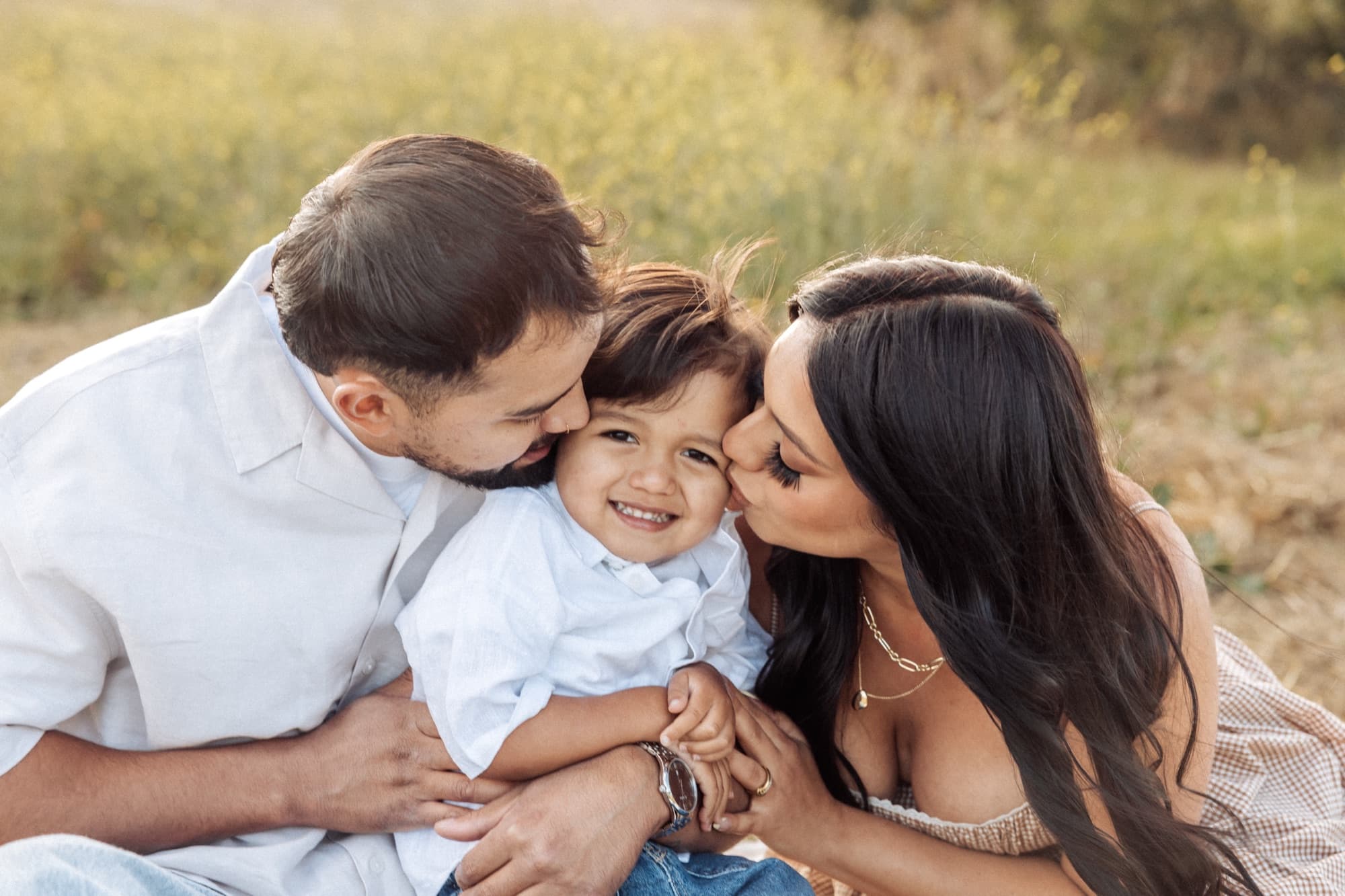 Parents kissing their son — family session close-up