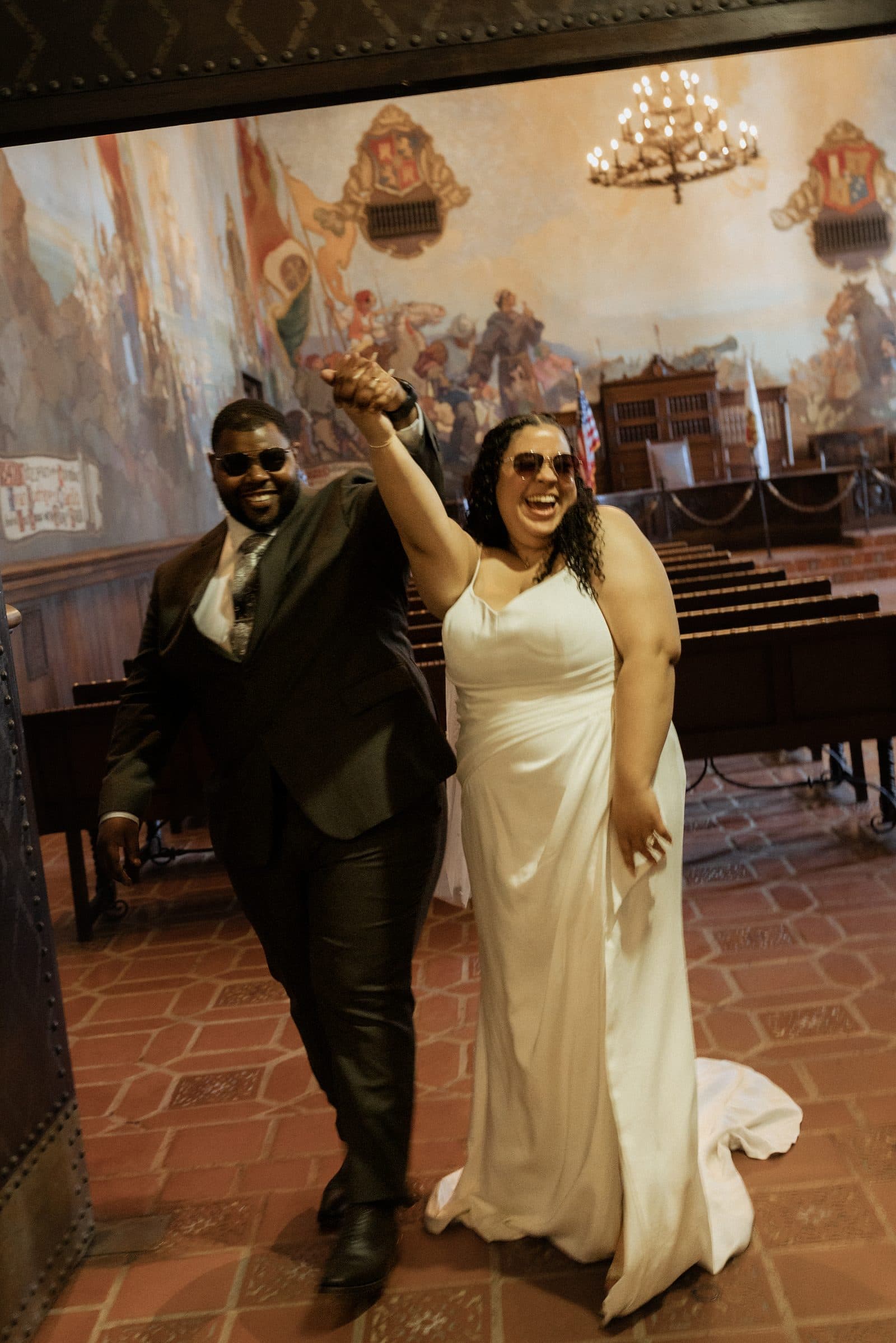 Newlyweds celebrating in the Mural Room with the hand-painted murals behind them