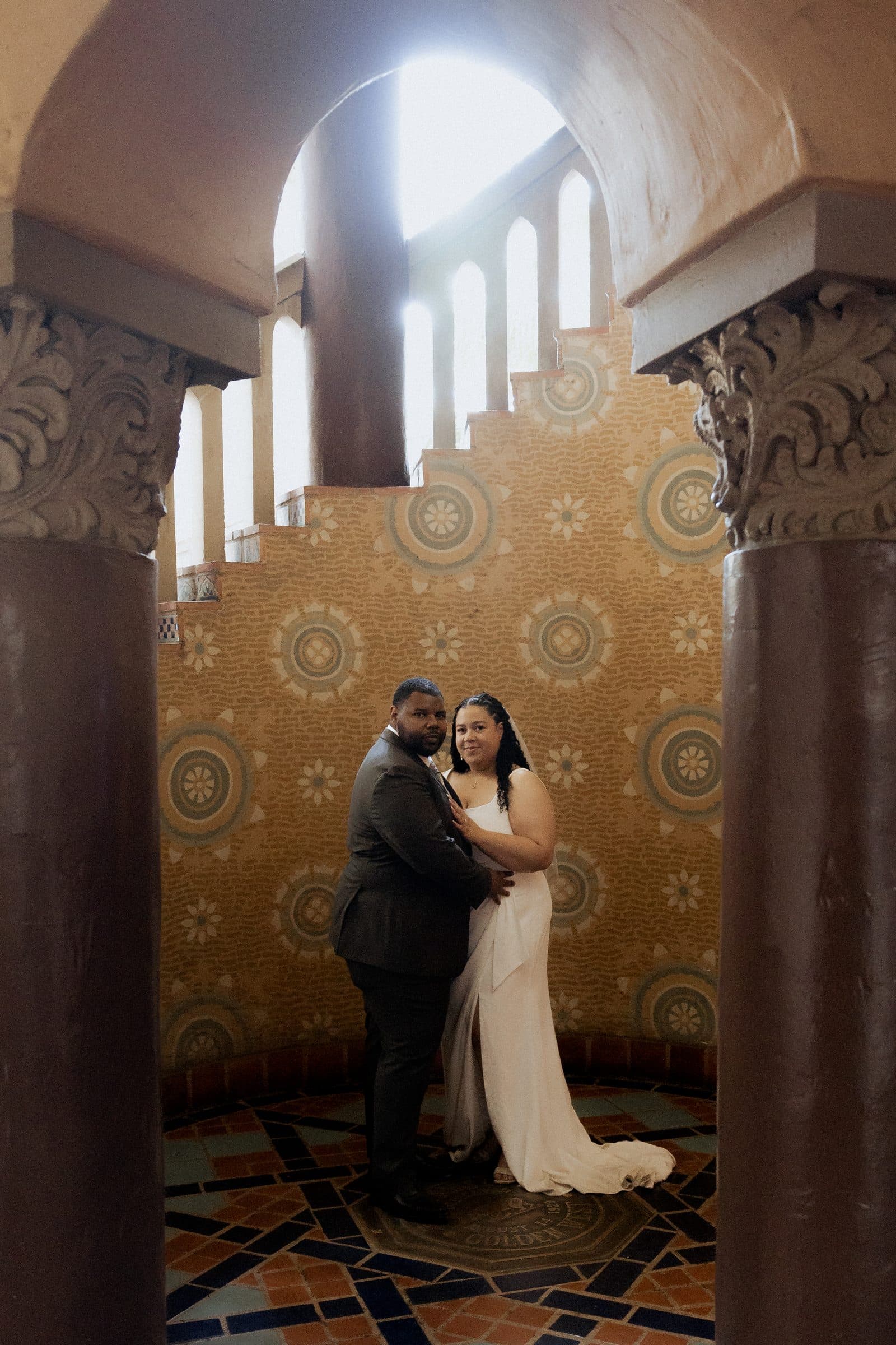 Couple embracing inside the tiled spiral staircase of the Santa Barbara courthouse