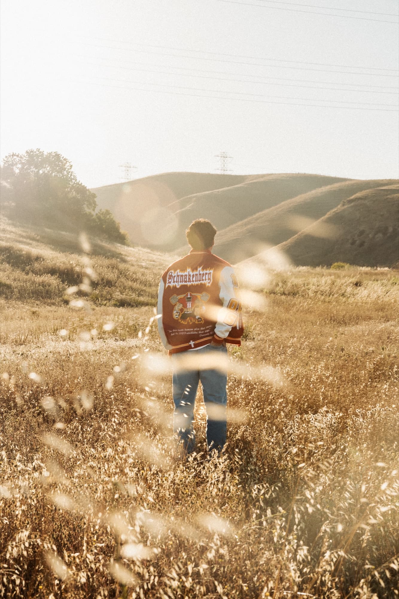 Senior portrait backlit in tall grass at sunset — Riverside