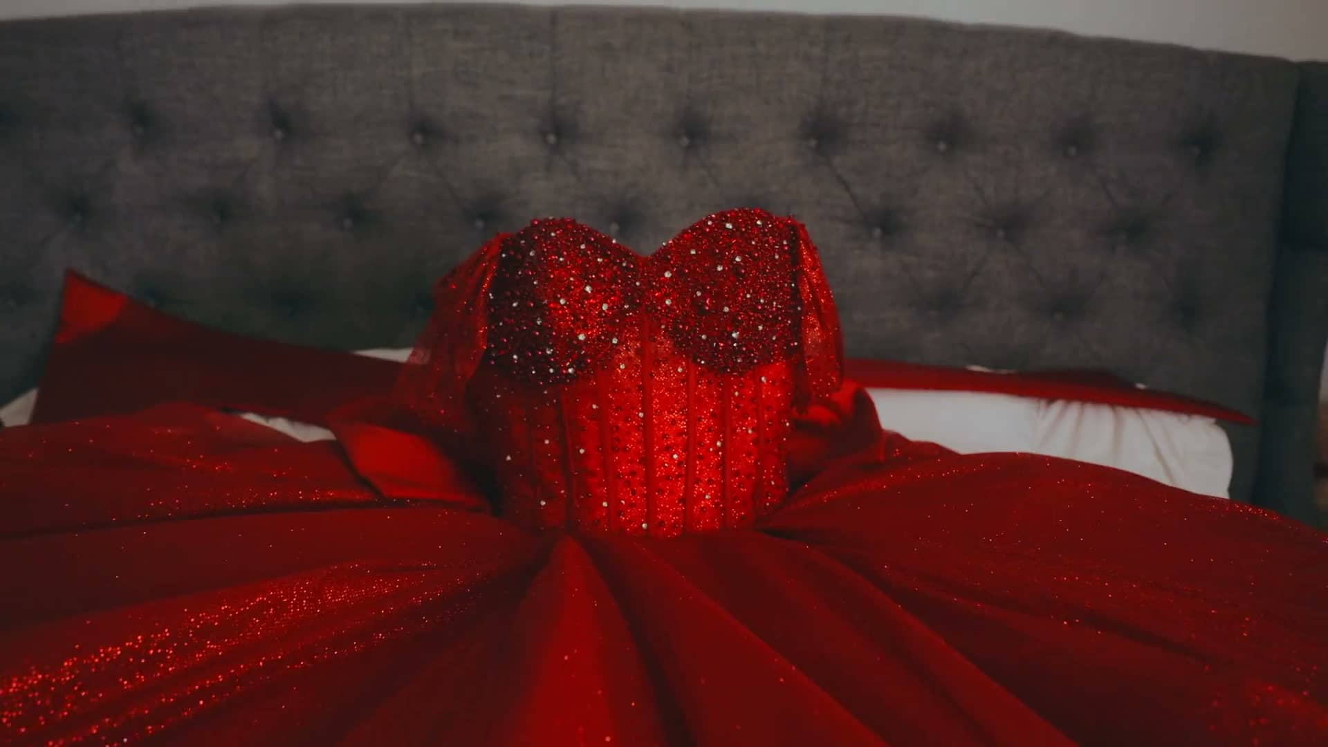 Red rhinestone quinceañera gown spread across a bed before the celebration