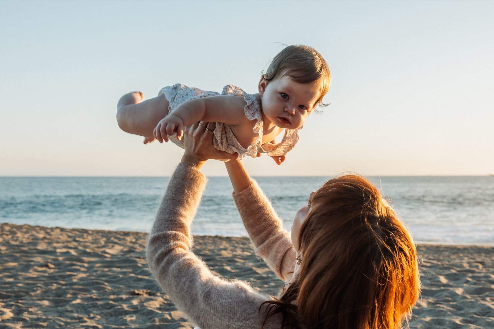 Mother lifting her baby against the sky