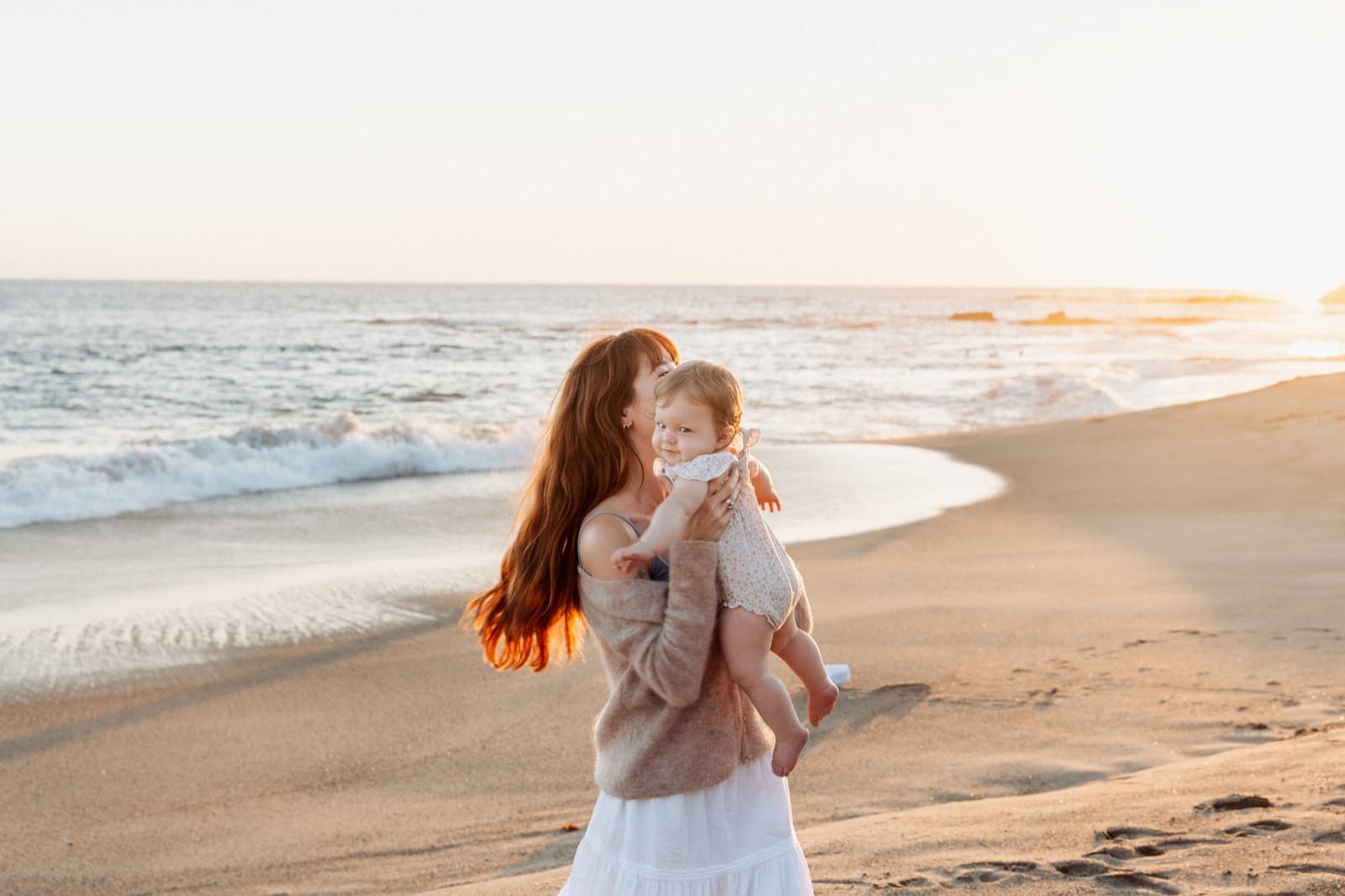 Mother and baby on the wet sand at sunset