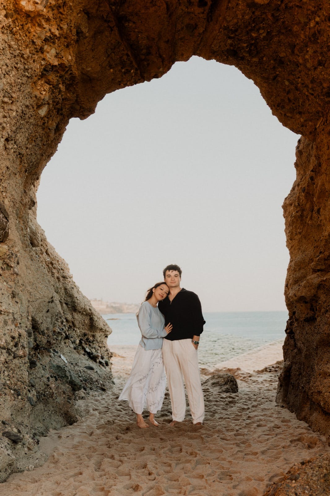 Couple framed inside a rock arch on the Orange County coast