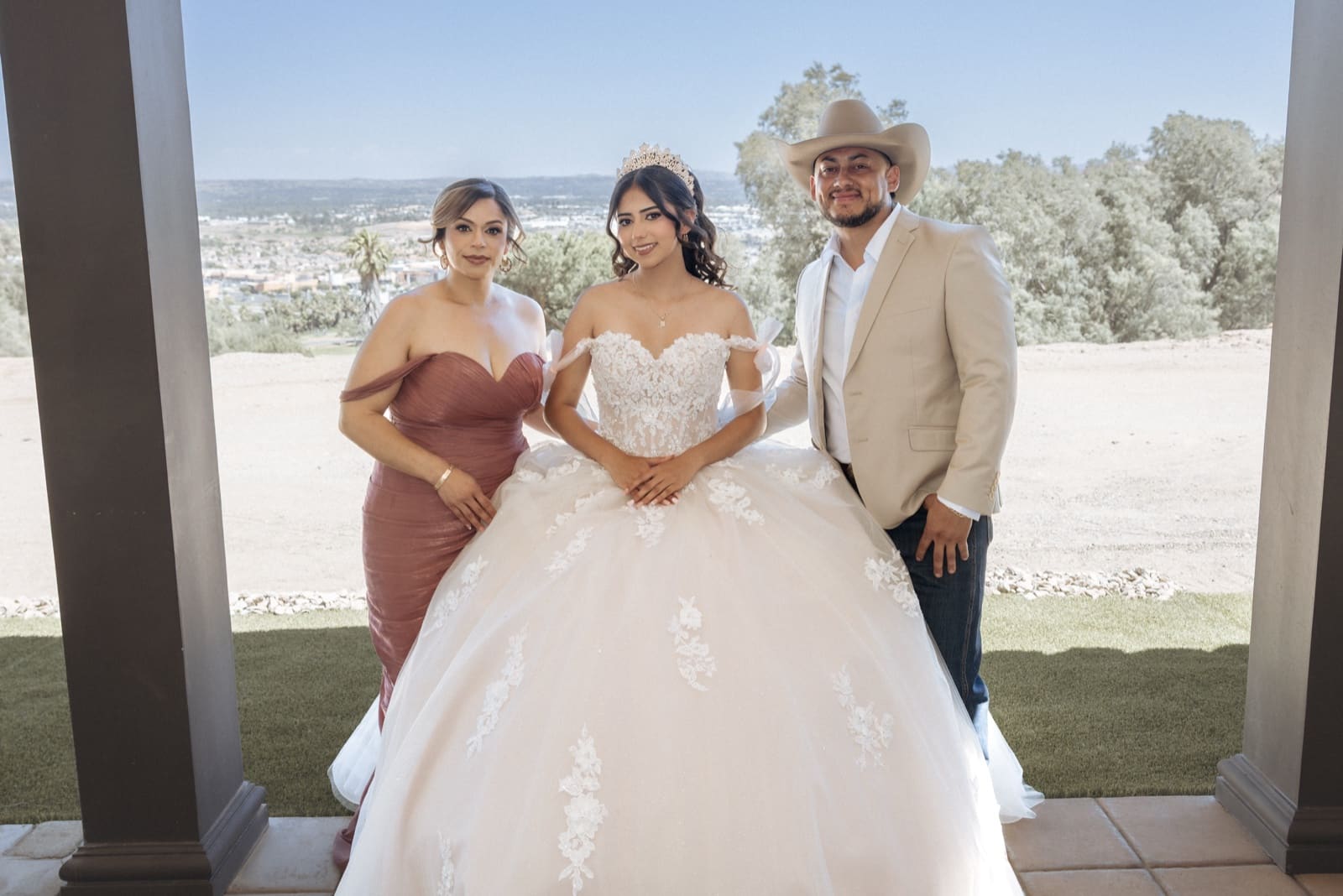 La quinceañera entre sus padres en el rancho