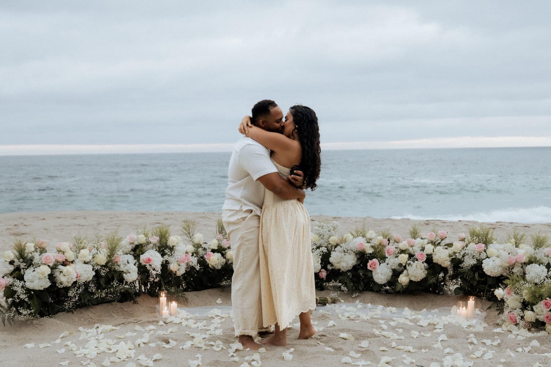 Marriage proposal on one knee at Laguna Beach, floral installation and the ocean behind